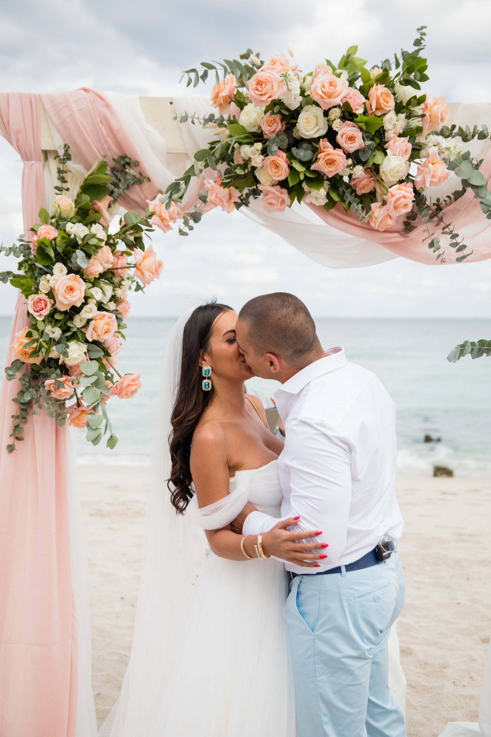 Couple beneath flowers at the end of a garden aisle