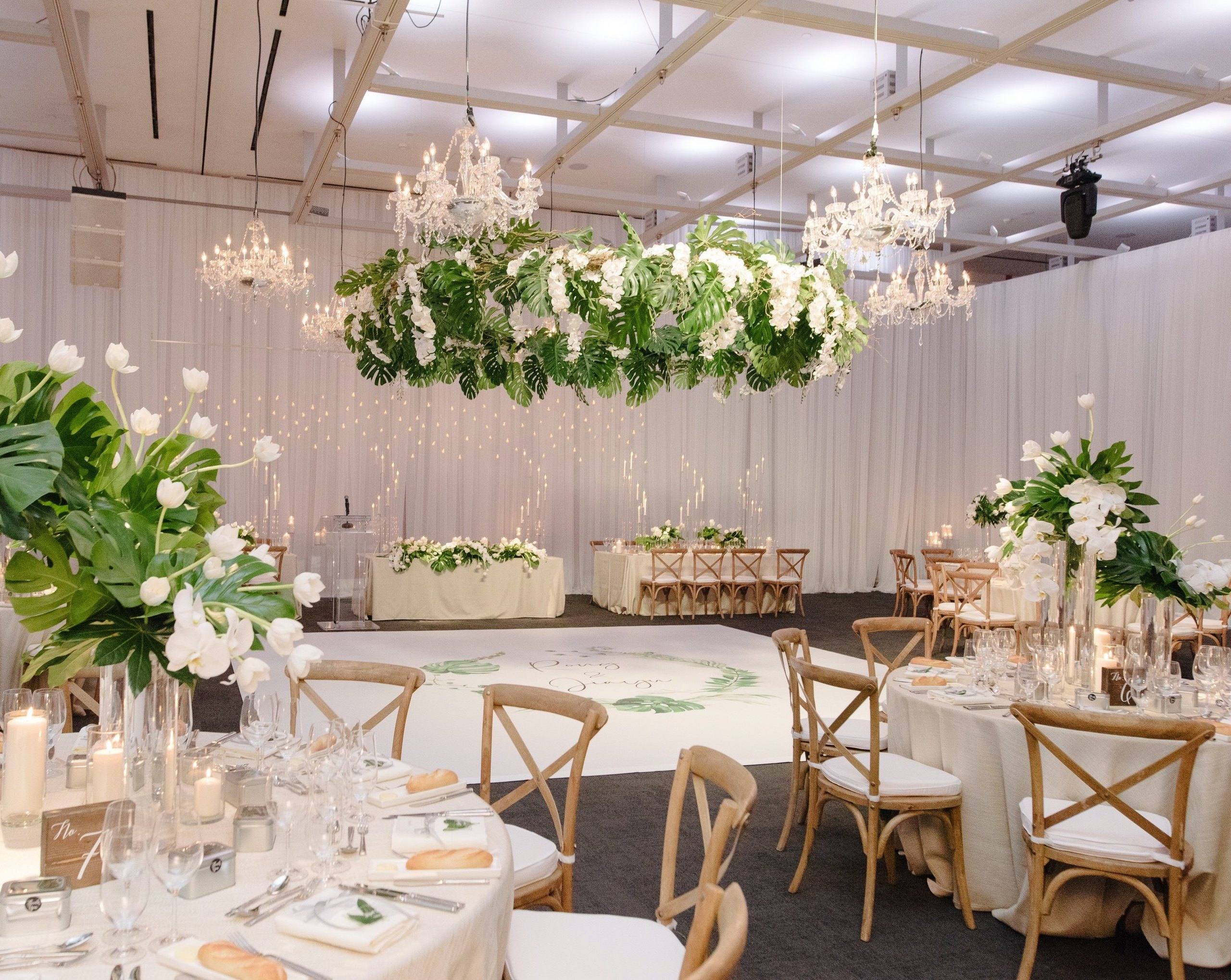Long reception table beneath hanging greenery