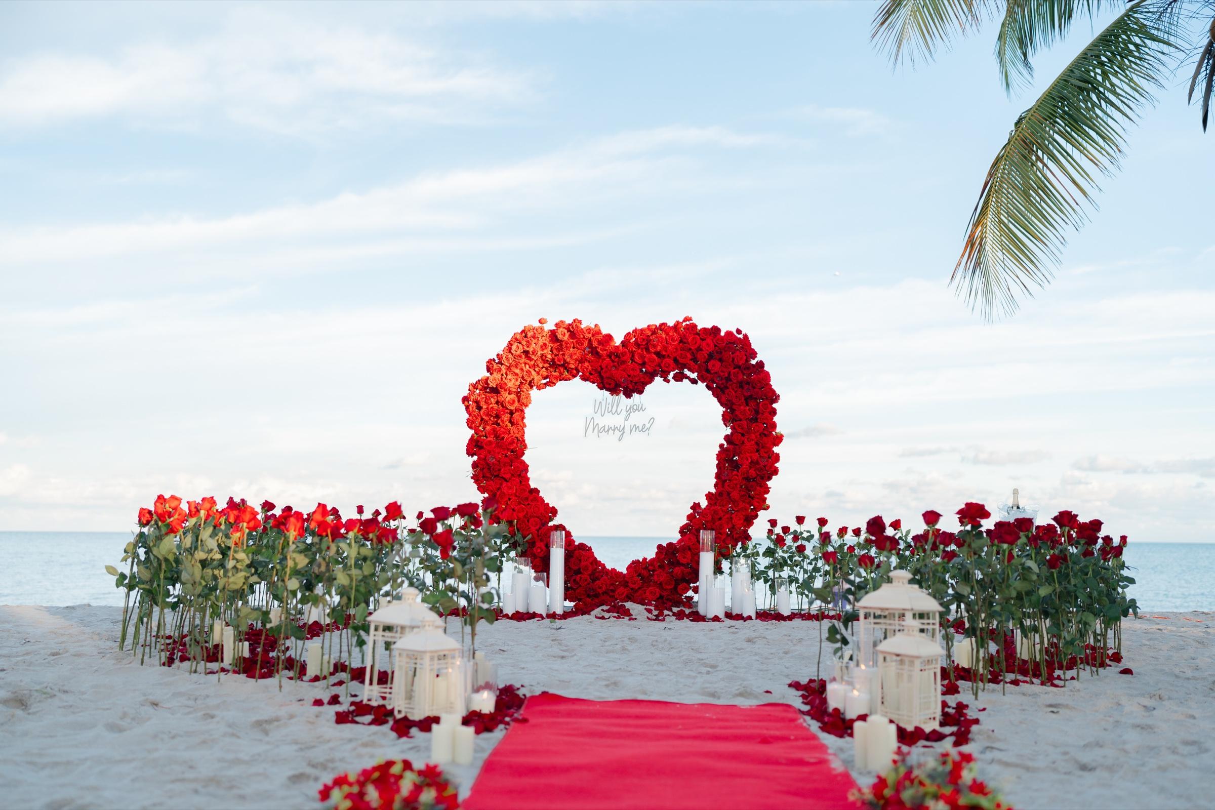 Heart shaped arch of red roses on the beach