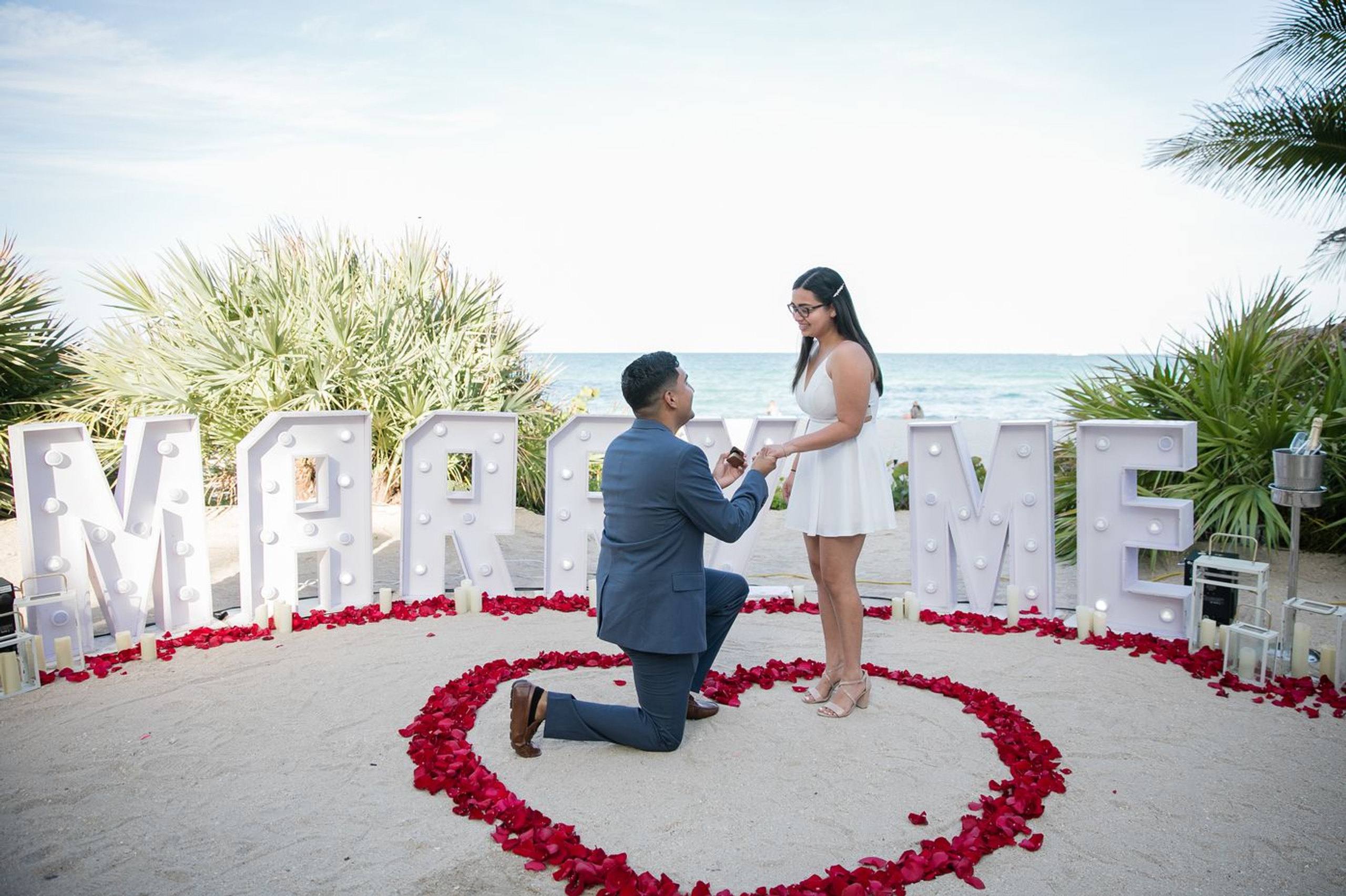 Beach proposal with Marry Me letters and a rose heart
