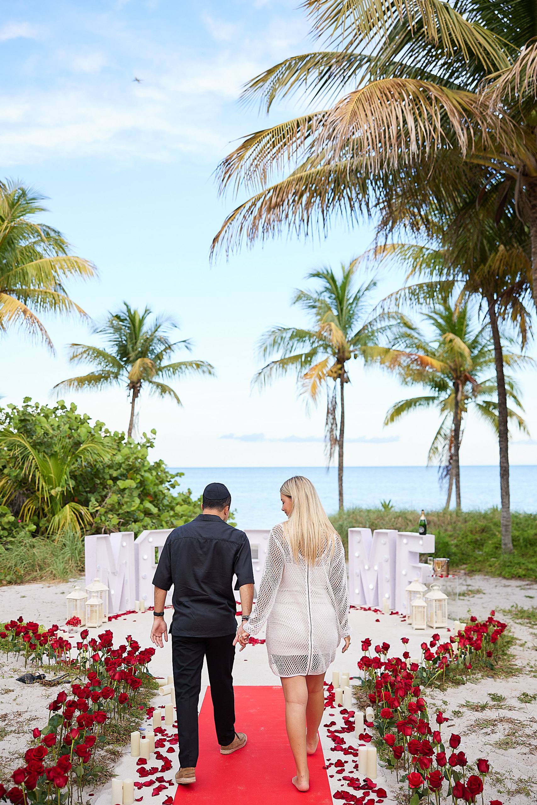 Beach ceremony framed by palms and white flowers