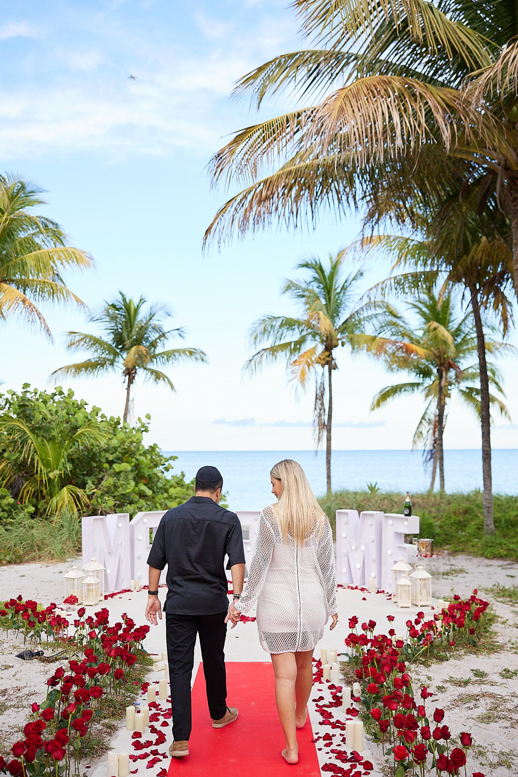 Beach ceremony framed by palms and white flowers